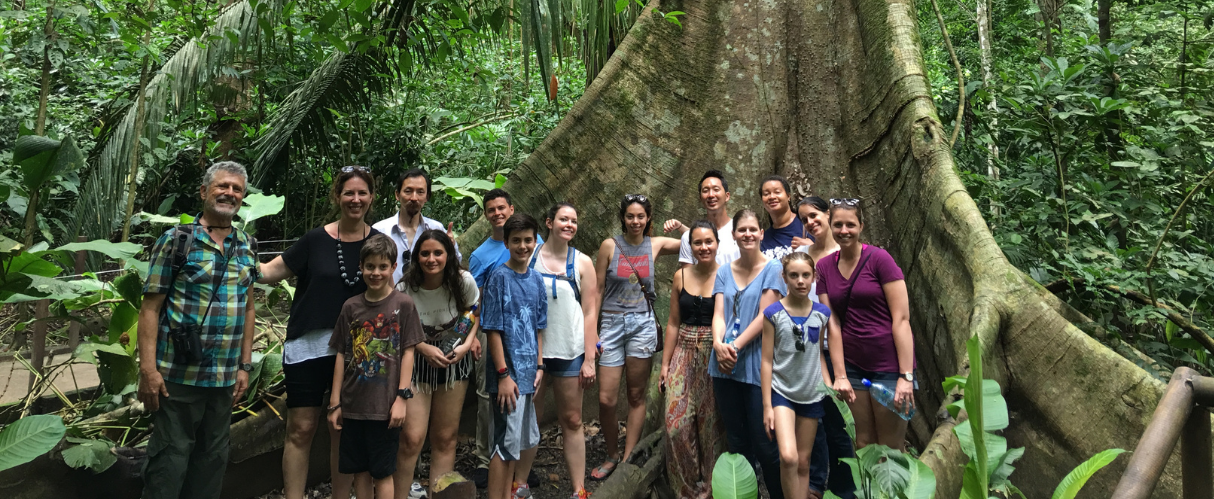 Photo of a group of students and teachers standing at the base of a tree in the Costa Rican rain forest.