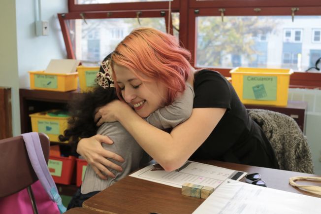 Photo of Hunter student Mary Escobar embracing a student at the end of a recent tutoring session.